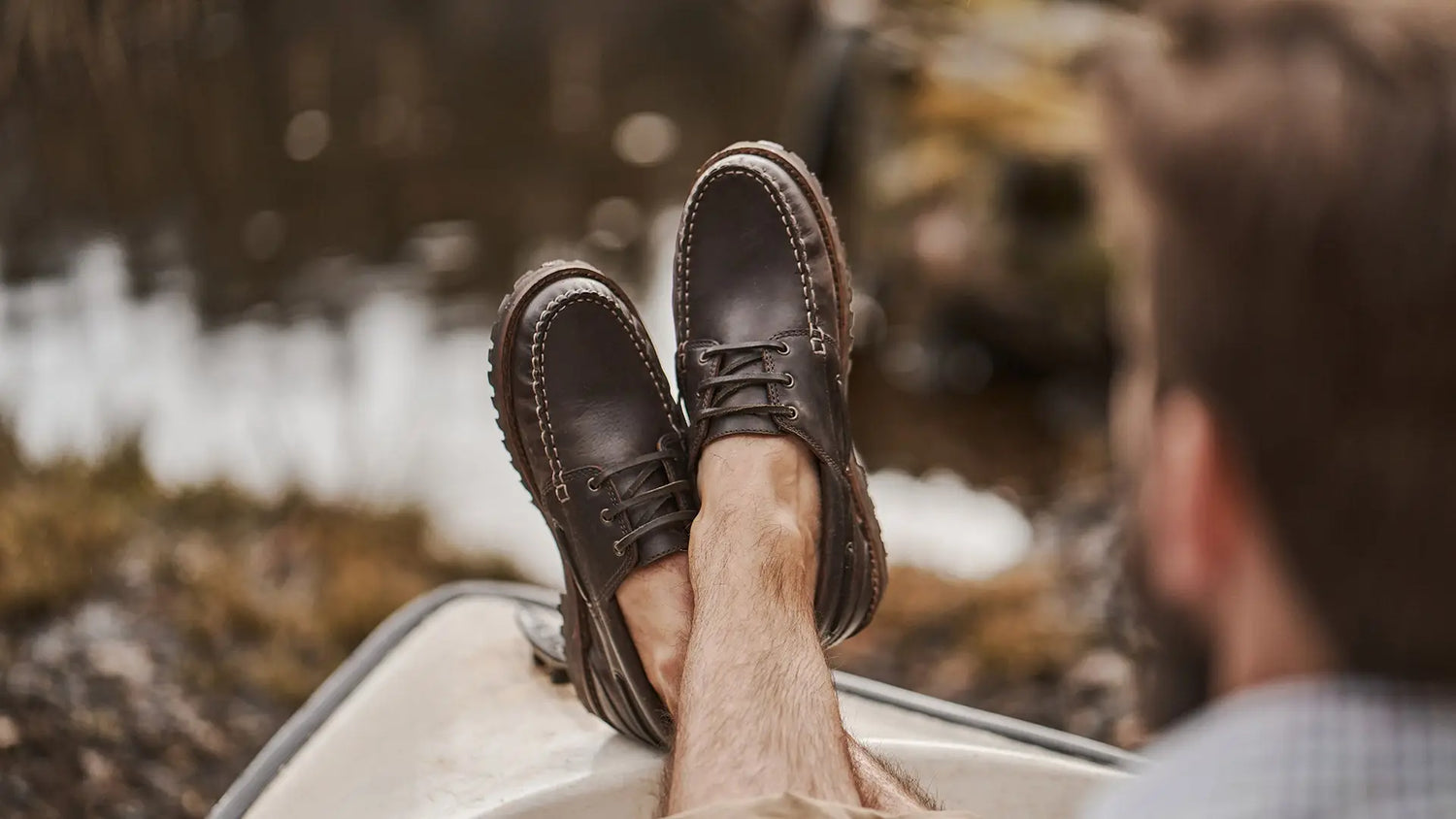 Pair of brown leather loafers with rubber sole resting on feet for stylish country clothing.