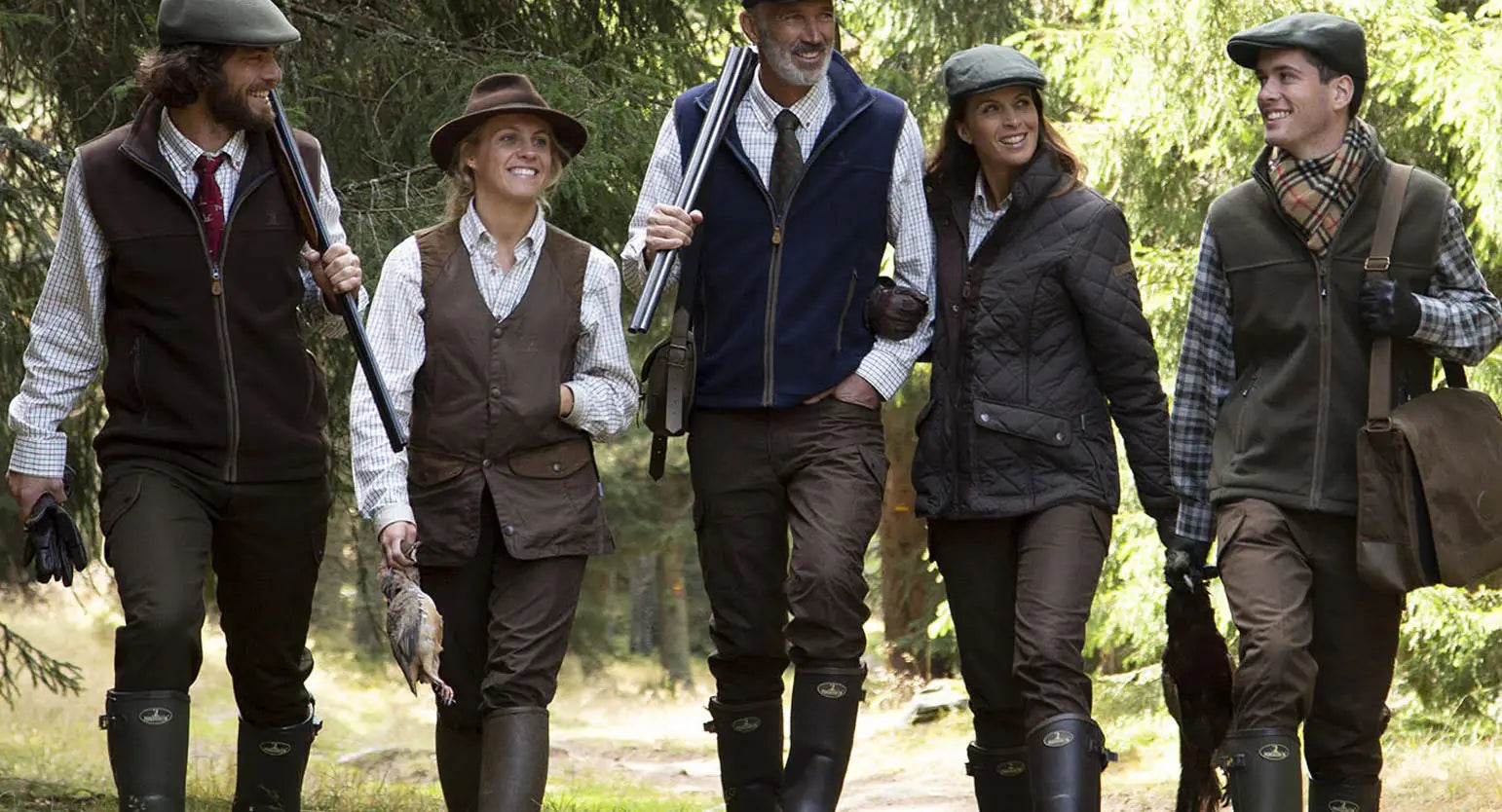 Group of people in vintage-style clothing showcasing stylish percussion hunting legwear outdoors