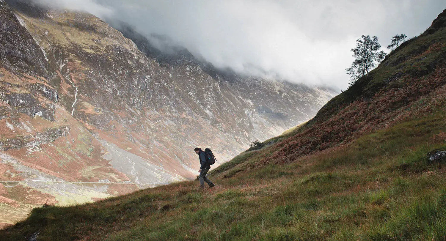 Hiker in forest clothing enjoying the great outdoors on a mountainside trail.