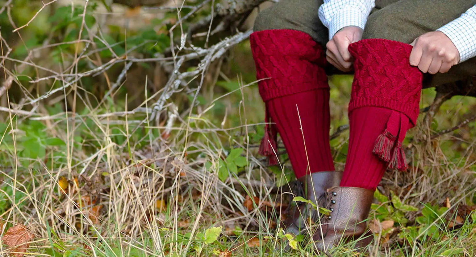 Red knitted leg warmers over boots, showcasing House of Cheviot’s rich heritage and timeless design.