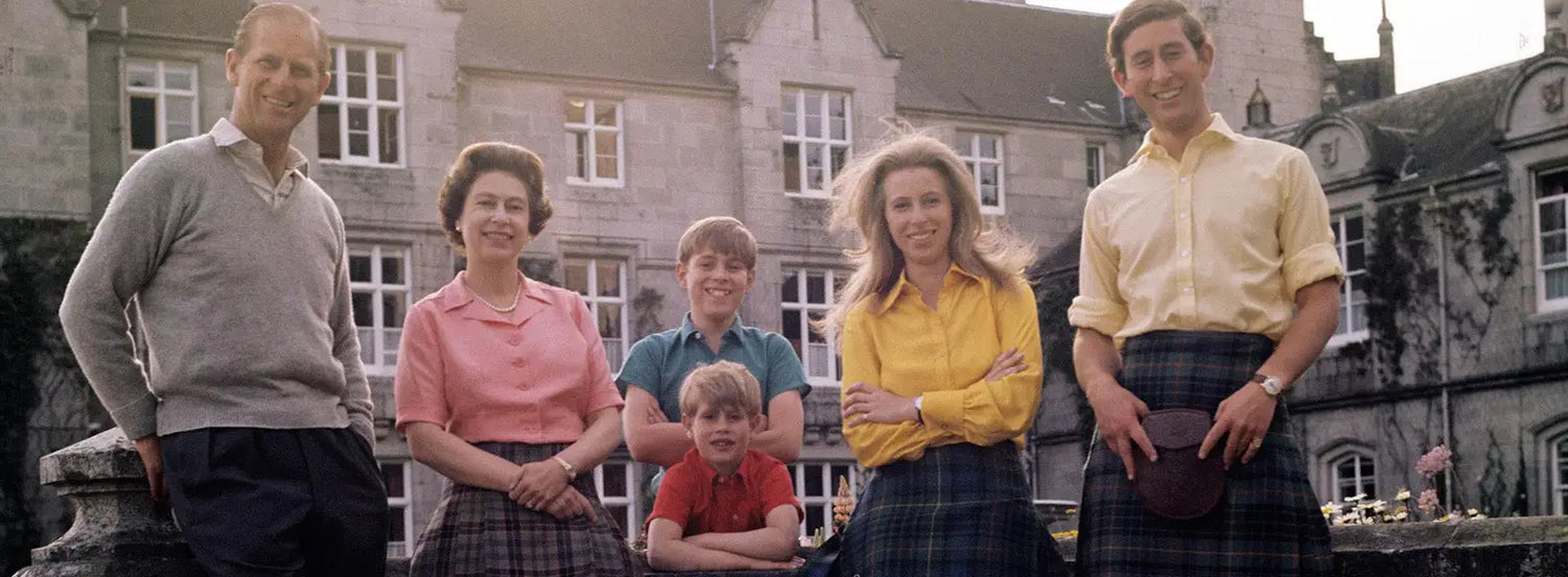 Group of people in stylish tweed jackets posing outdoors near the royal family building.