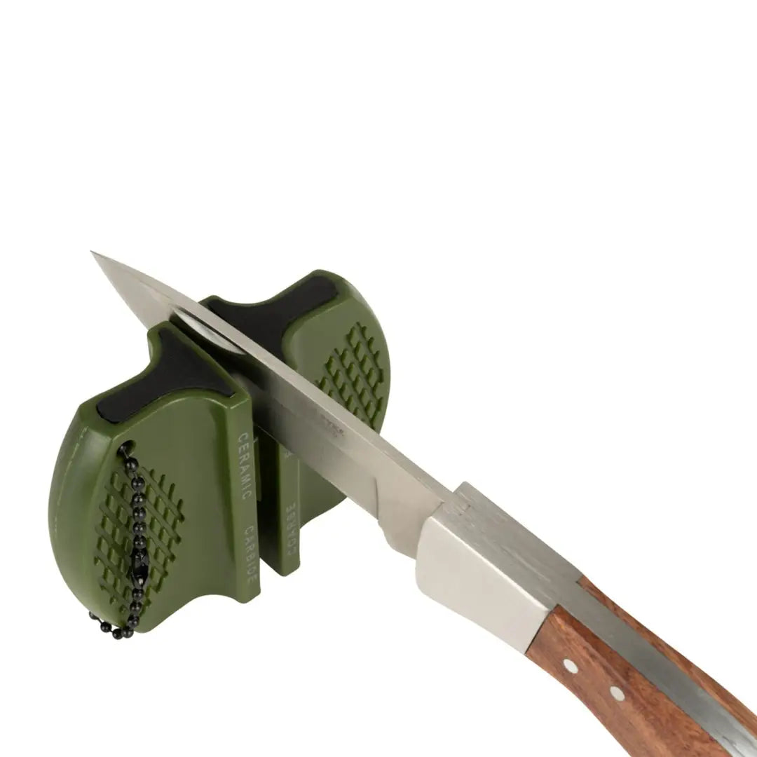 Handheld Jack Pyke Knife Sharpener with green body sharpening a knife in its slot