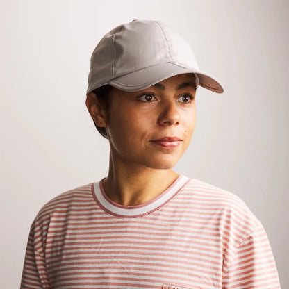 Woman in a white baseball cap and striped shirt wearing Sealskinz Salle Cap