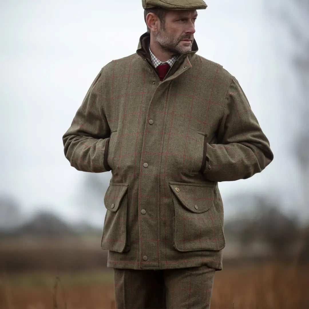 Man in a traditional British waxed jacket and flat cap, sporting the Alan Paine Combrook field coat