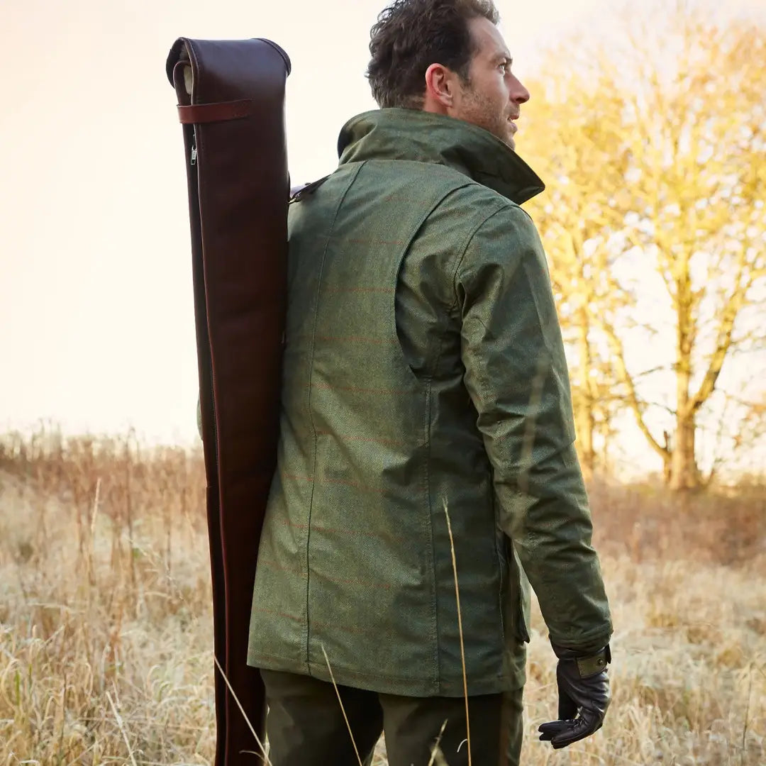 Man in a green Alan Paine Didsmere Coat with faux fur lining and a long, dark case