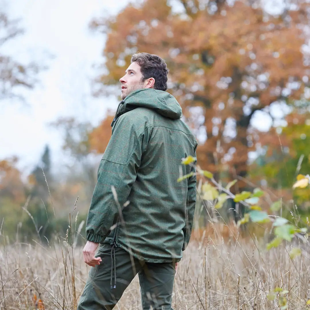 Man in a green Alan Paine Didsmere Smock with faux fur lining standing in a field