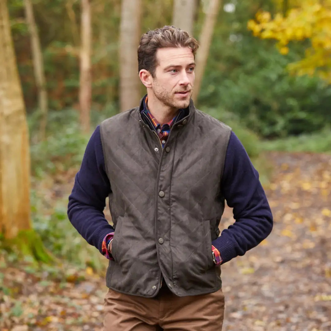 Man in a gray vest over a navy sweater enjoying the outdoors in country clothing