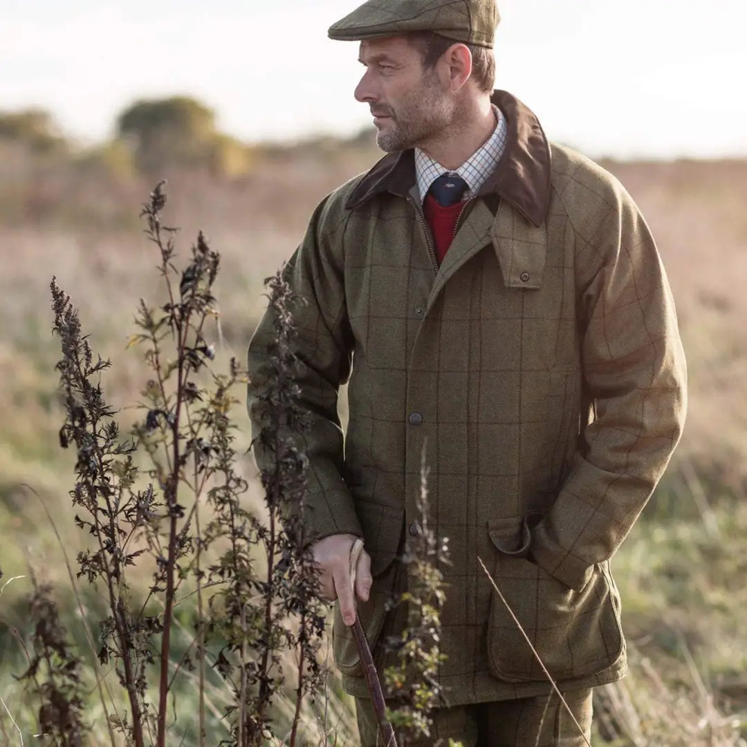 Man in Alan Paine Rutland Waterproof Tweed Coat standing in tall grassy field