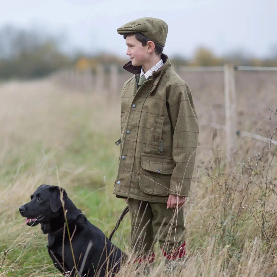 Young person in Alan Paine Rutland kids tweed breeks with black dog in a field