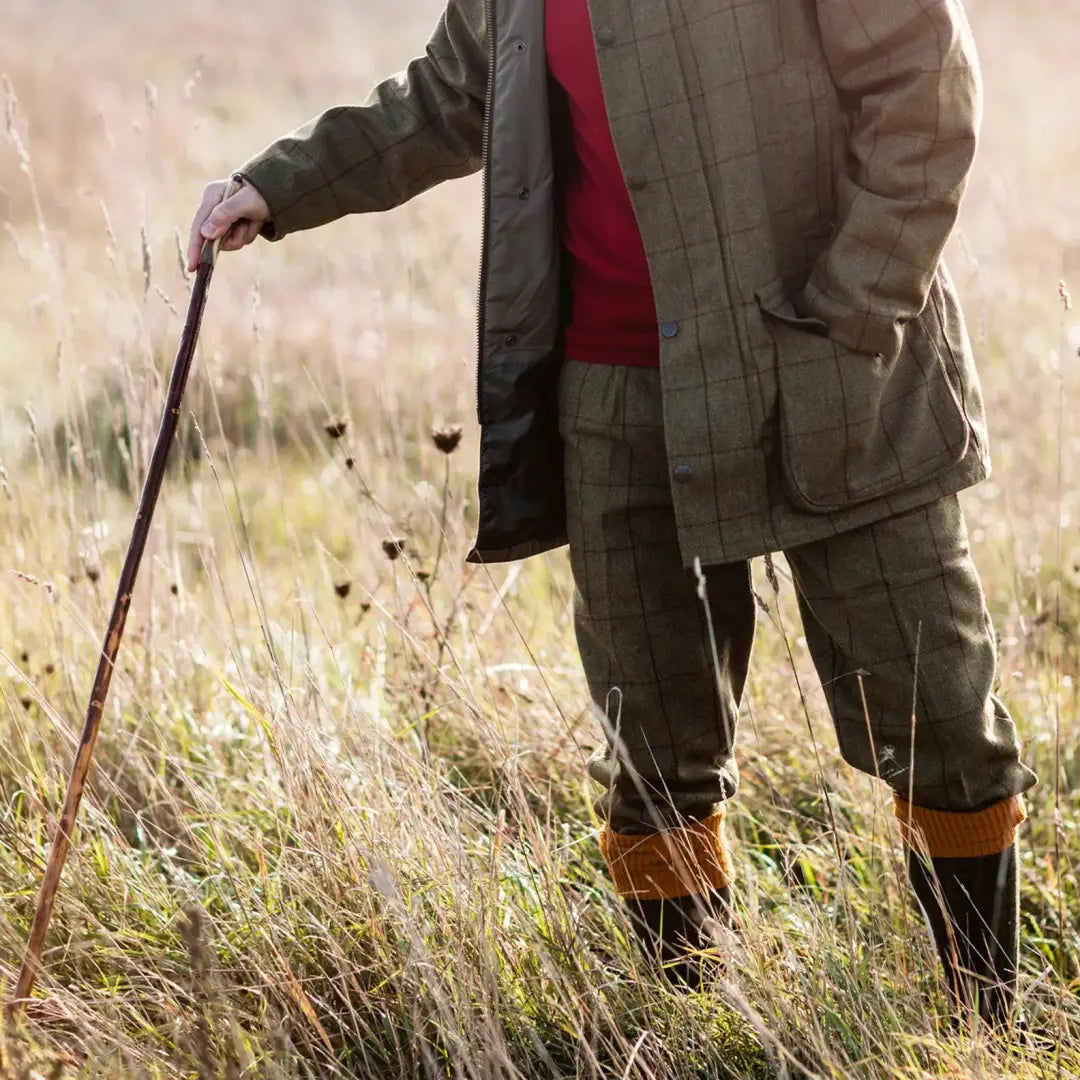 Person in green jacket and boots showcasing Rutland Tweed Breeks in a field