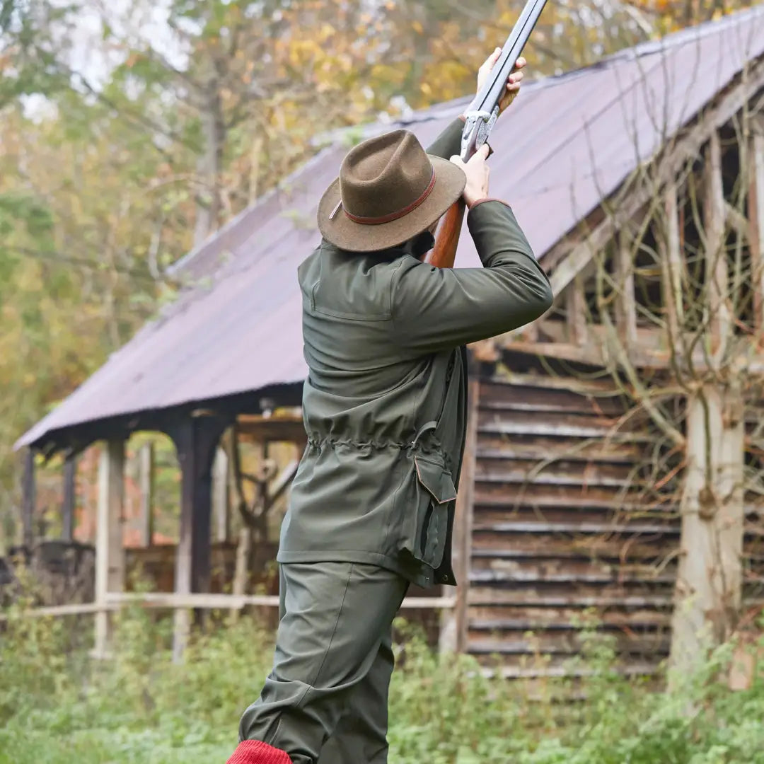 Person in a hat and green outfit aiming a shotgun with Alan Paine Stancombe Waterproof Coat