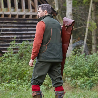 Man in hunting attire with rifle case, showcasing Alan Paine Stancombe Waterproof Waistcoat