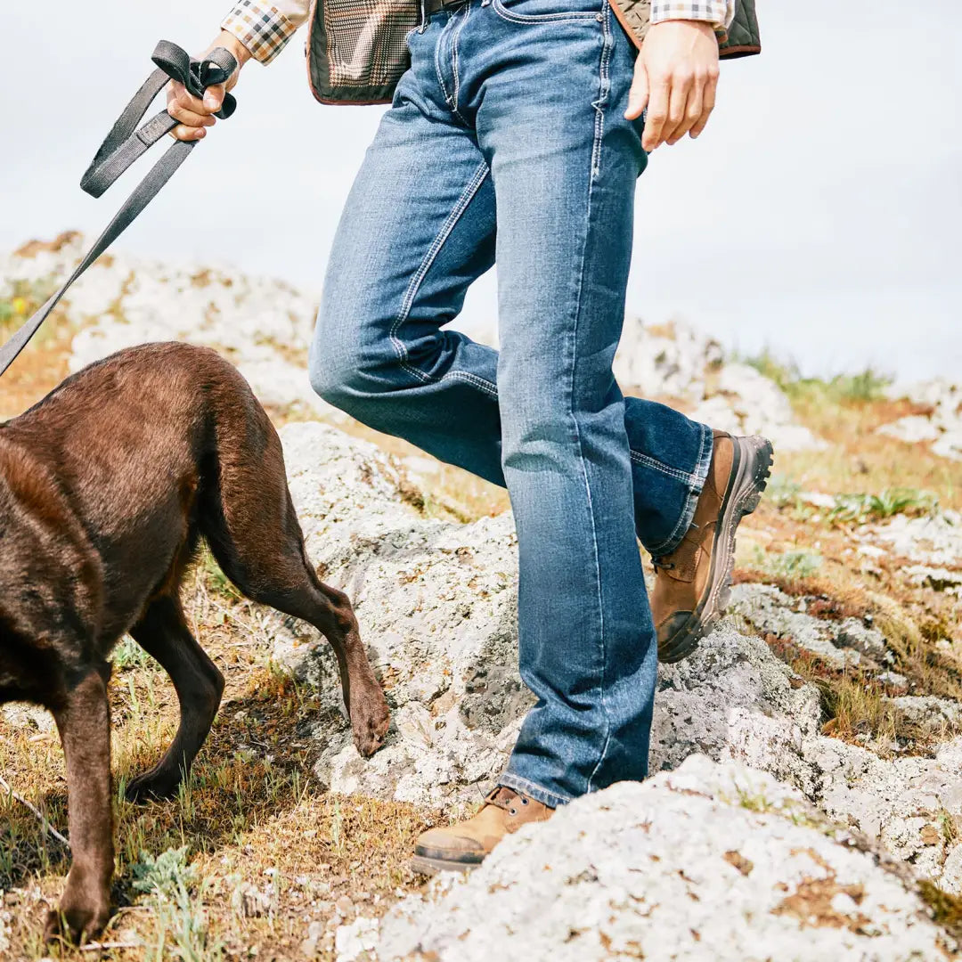 Person in jeans and Ariat Mens Moresby Waterproof Boots hiking outdoors with a dog