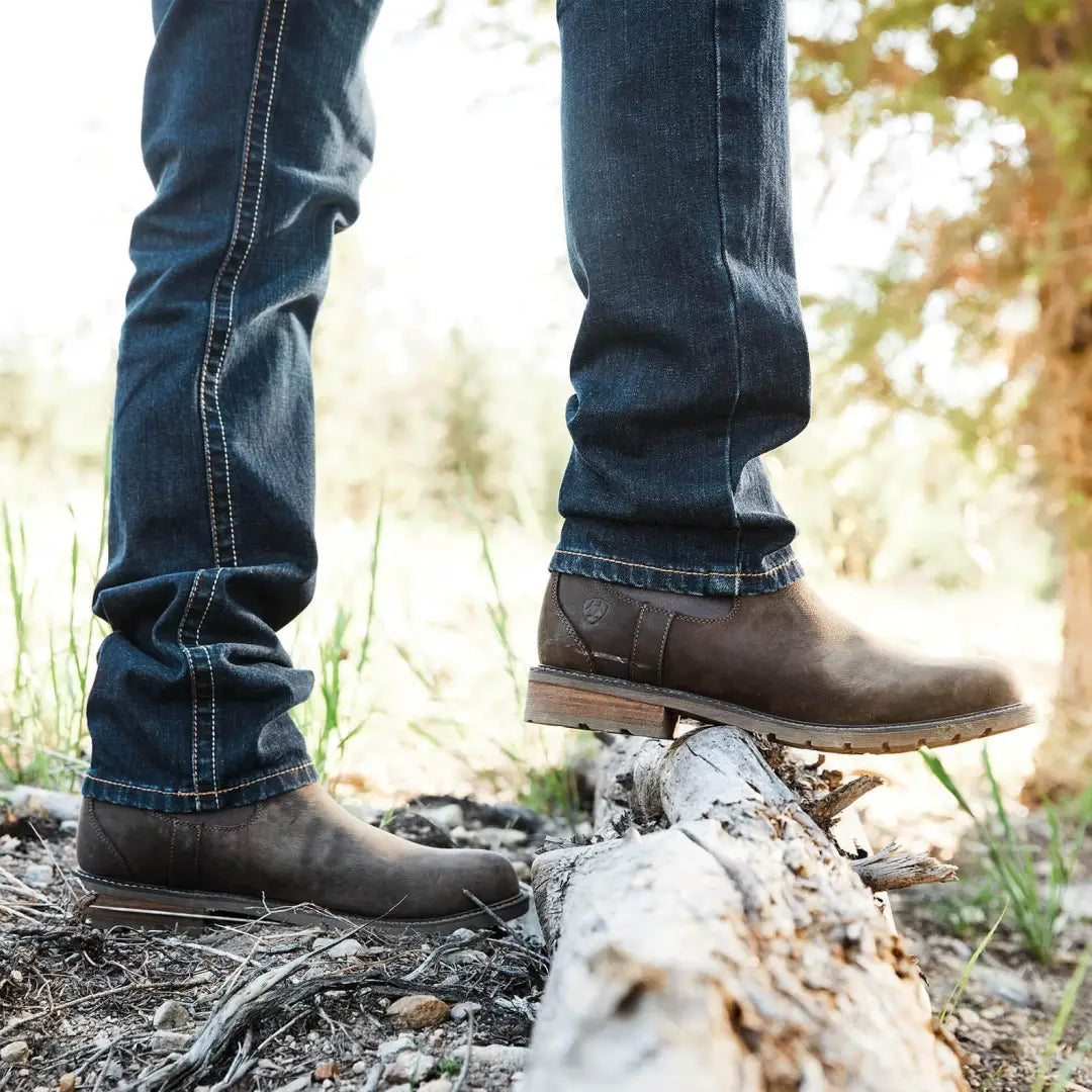 Brown leather boots with blue jeans on a log, showcasing Ariat Wexford’s fully waterproof design