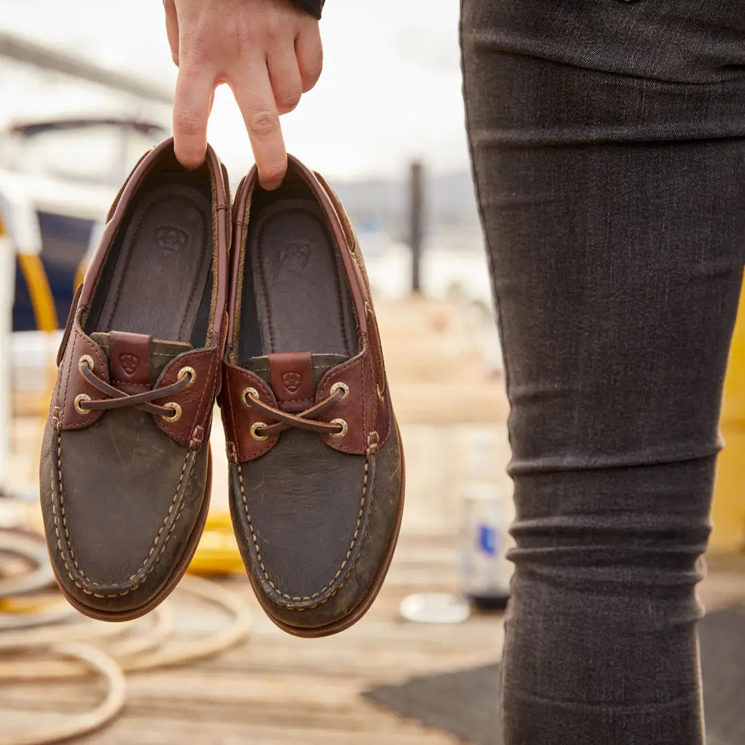 Hand holding a pair of Ariat Womens Antigua Boat Shoes in brown leather