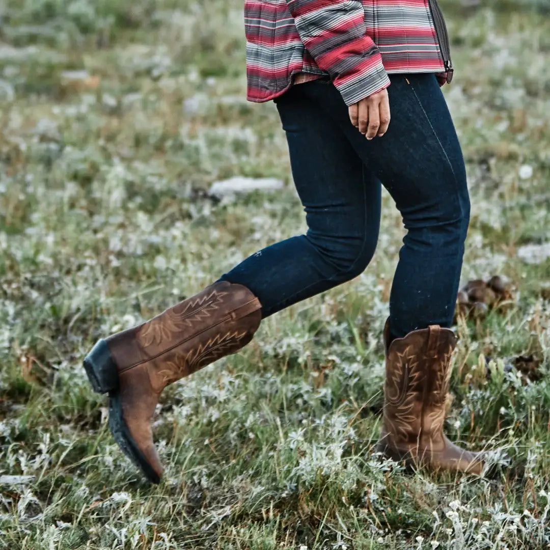 Brown leather cowboy boots styled with jeans and a striped top for country clothing lovers