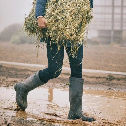 Person in Ariat Womens Kelmarsh Wellington Boots carrying hay in muddy conditions