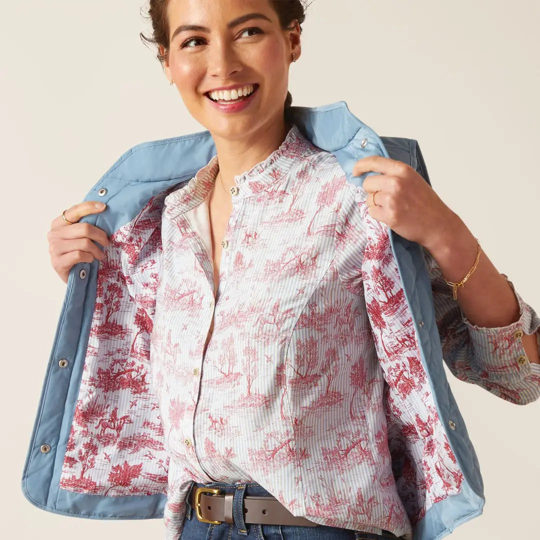 Smiling woman in floral shirt and blue denim jacket showcasing the Woodside vest offers style