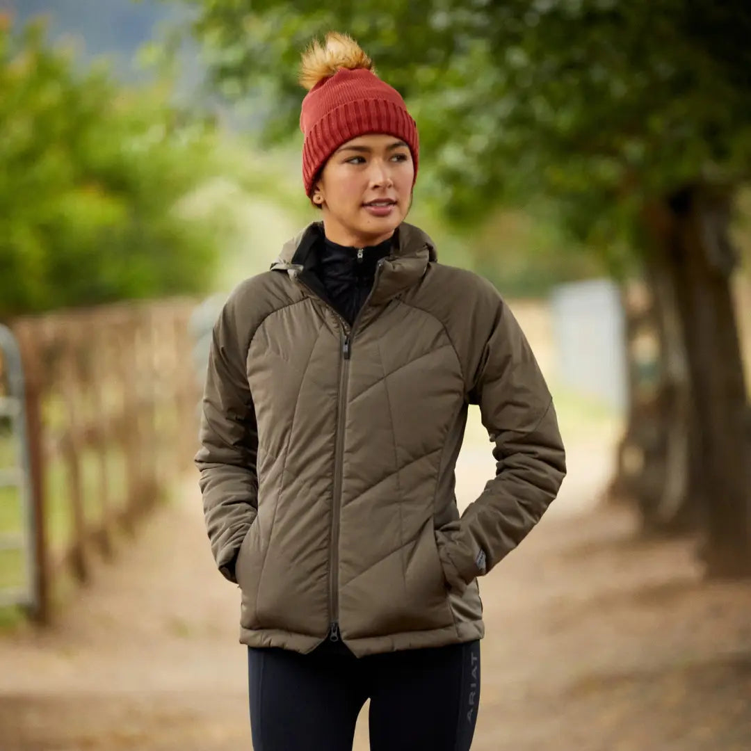 Person in a puffy gray zonal insulated jacket and red knit hat outdoors