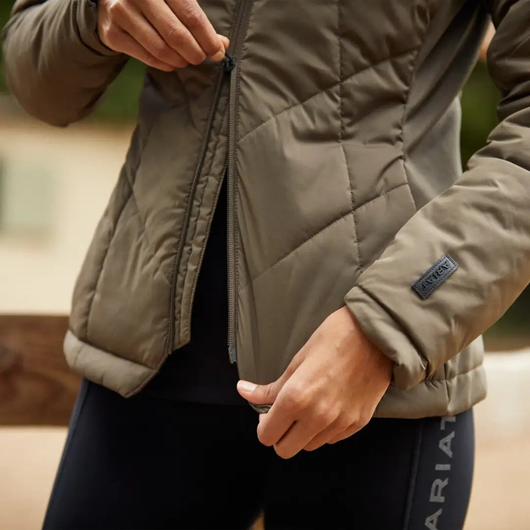 Model zipping up the Ariat Zonal Insulated Jacket in stylish puffy gray