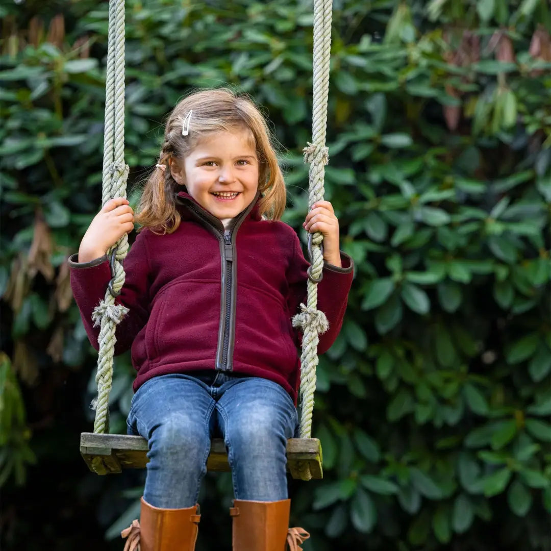 Child on a rope swing, beaming while wearing a Baleno Cody fleece jacket