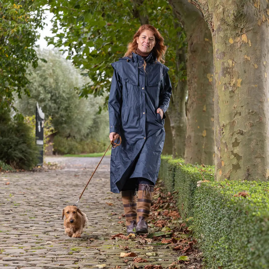 Woman in a Baleno Oxford women’s coat walking a small dog on a cobblestone path