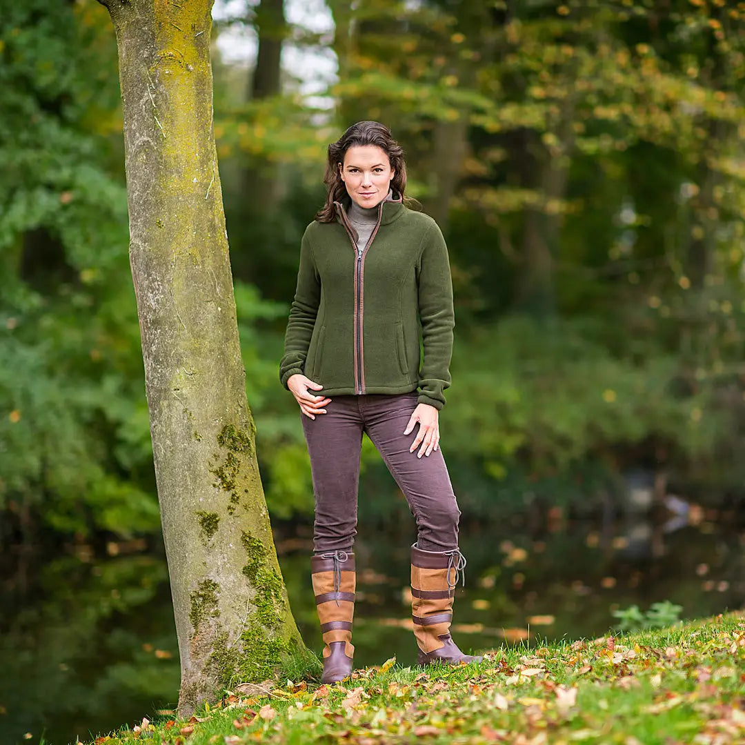 Person in olive green Baleno Sarah Ladies fleece jacket by a tree trunk