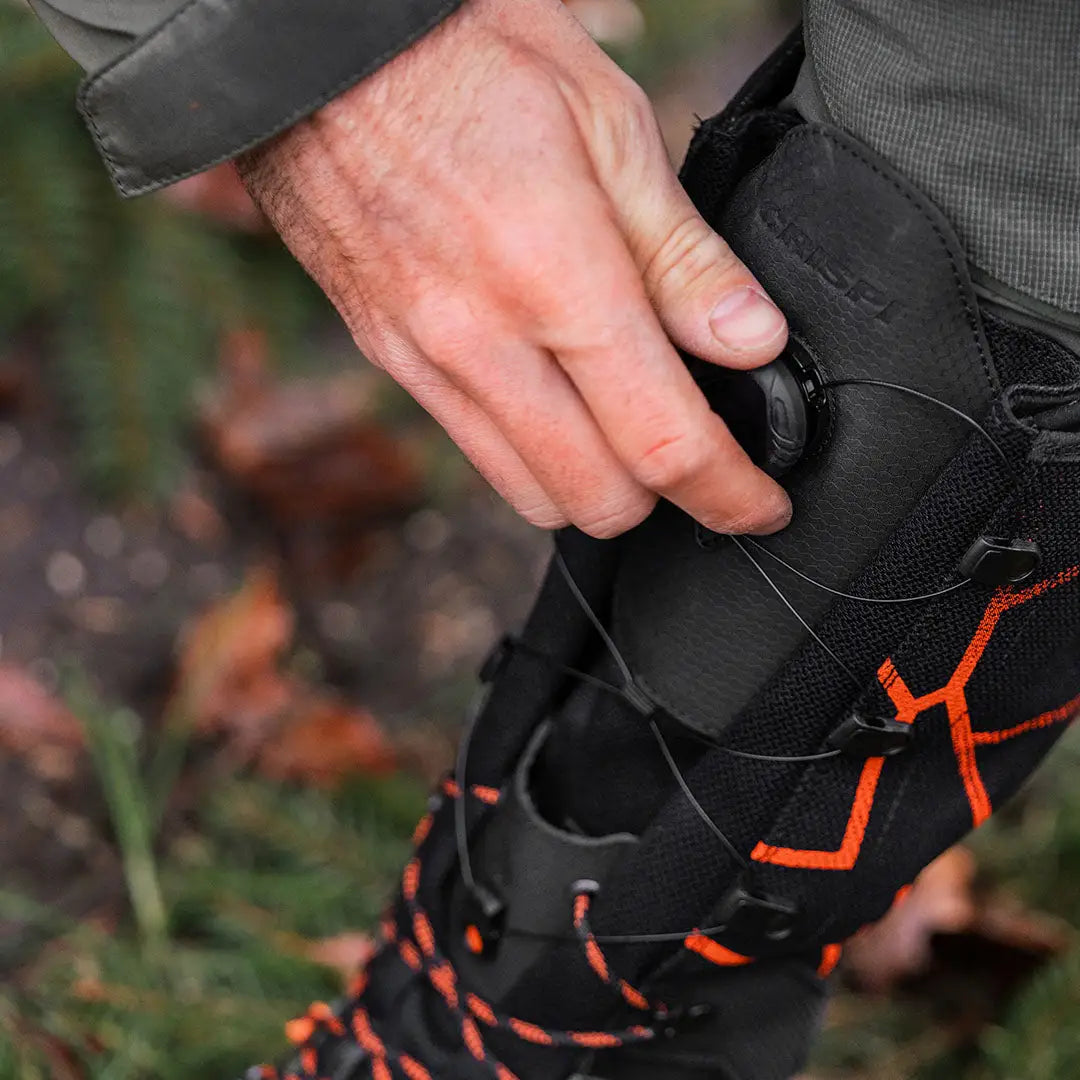 Hand adjusting a Crispi Futura NXT GTX black hiking boot with orange laces