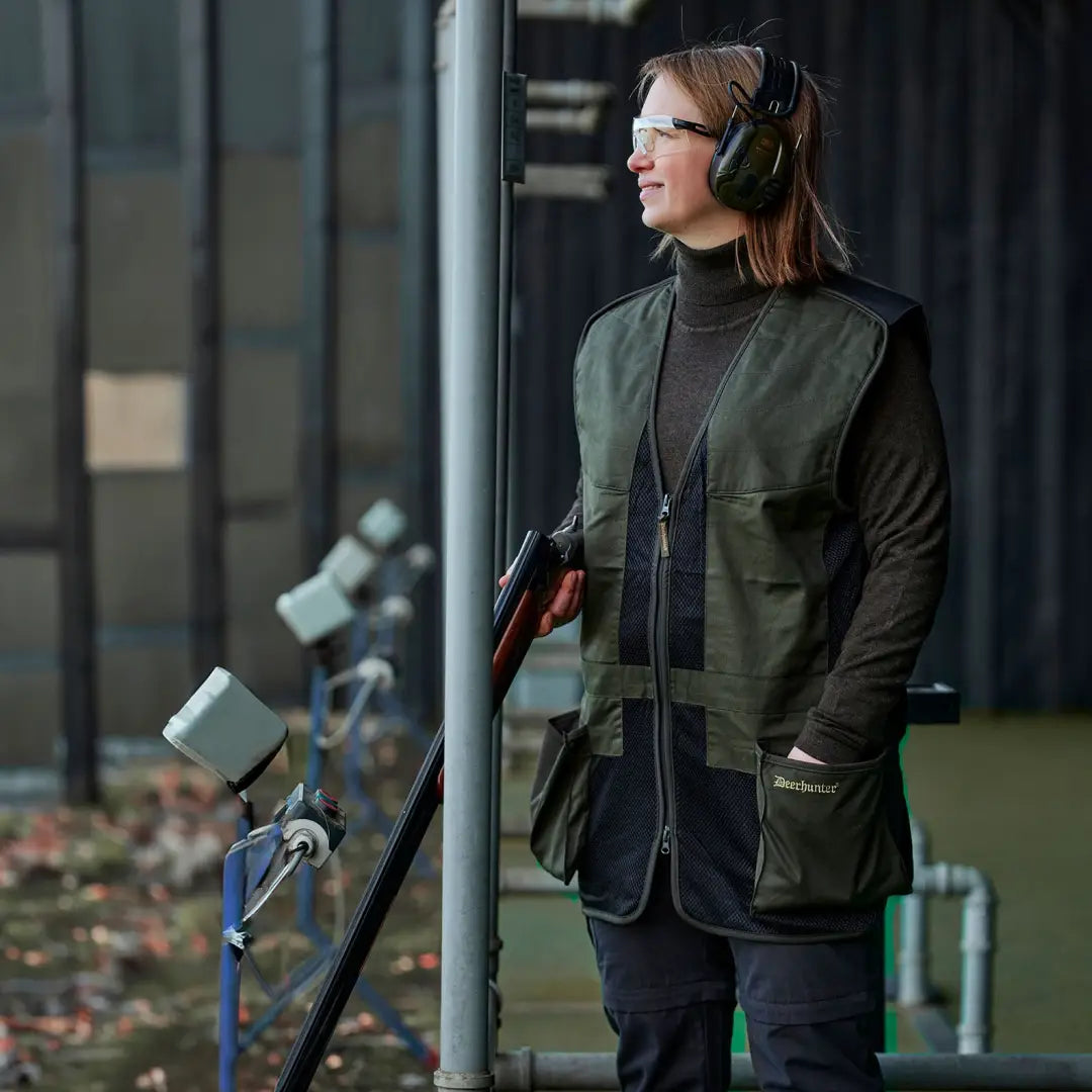 Woman in Deerhunter Atlas Mesh Shooting Waistcoat with shotgun and headphones