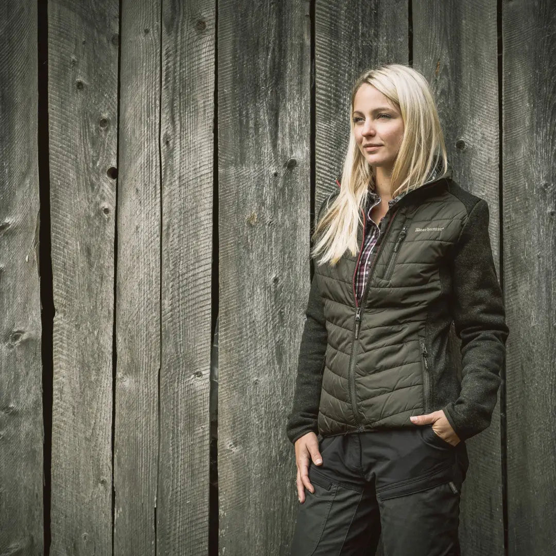 Woman with blonde hair in dark quilted Deerhunter Lady Caroline Padded Jacket by wooden wall