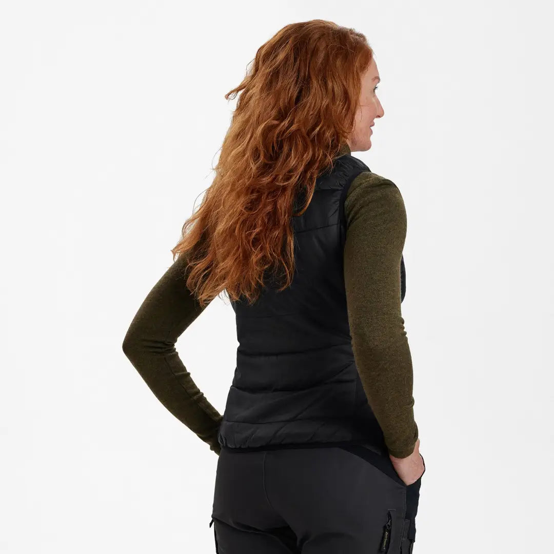 Woman in Deerhunter’s Lady Heat Inner Waistcoat, black vest over green shirt, back view