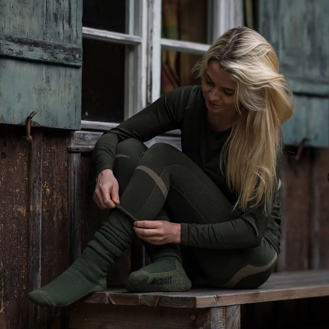 Woman with long blonde hair in dark green clothing showcasing Deerhunter underwear set