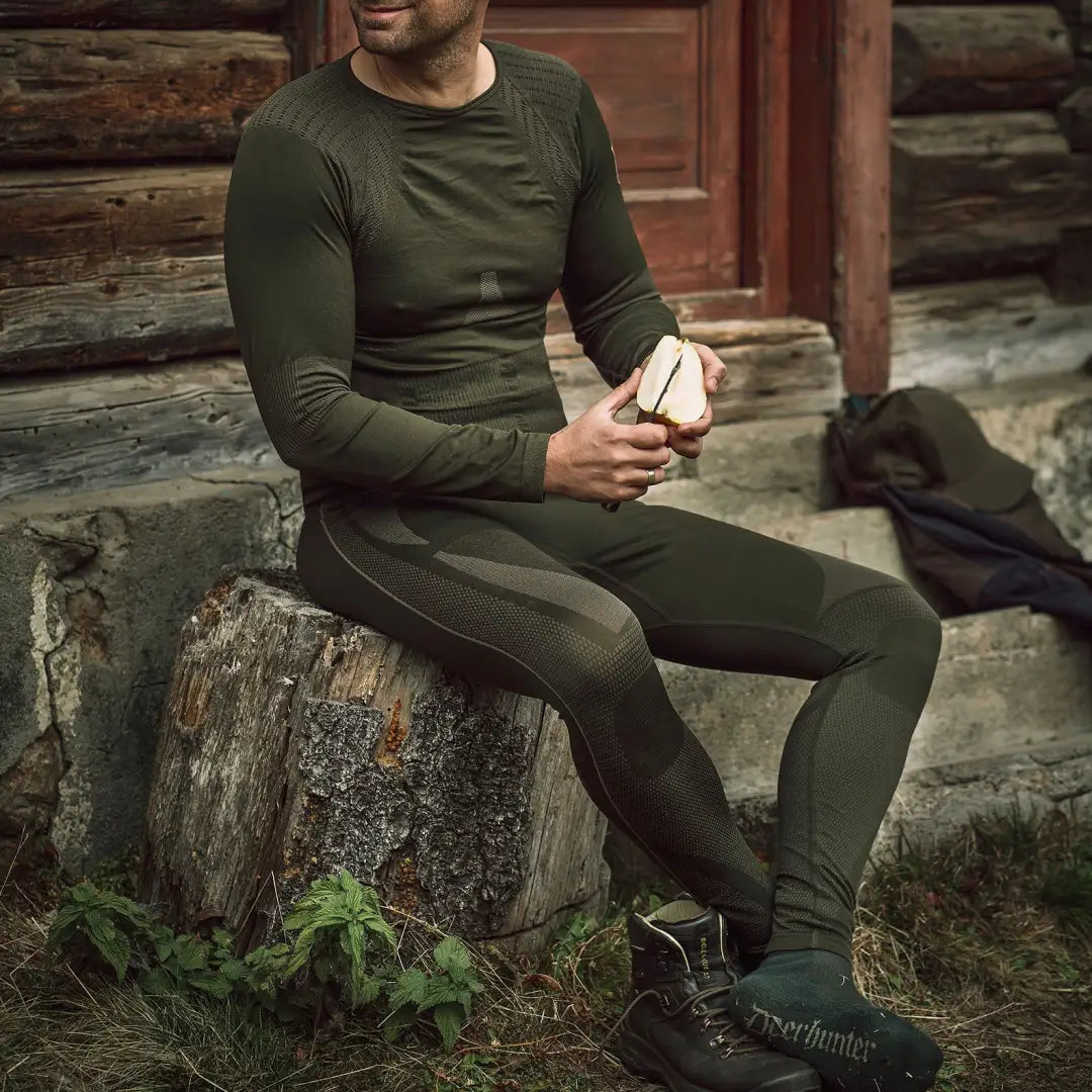 Man in dark green long-sleeved shirt and pants showcasing Deerhunter underwear set