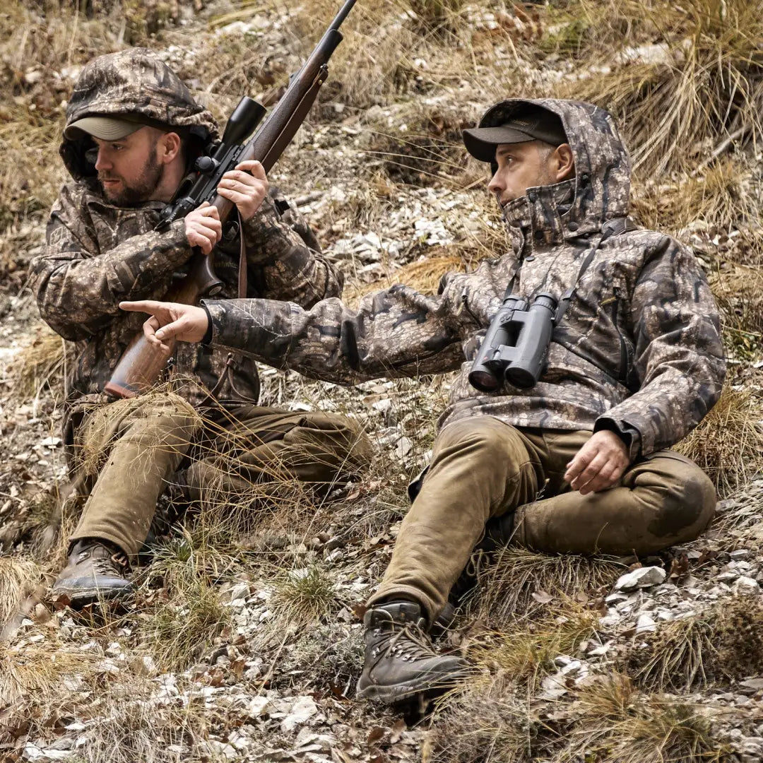 Two hunters in camouflage gear wearing Deerhunter Pro Gamekeeper Smock on a hillside