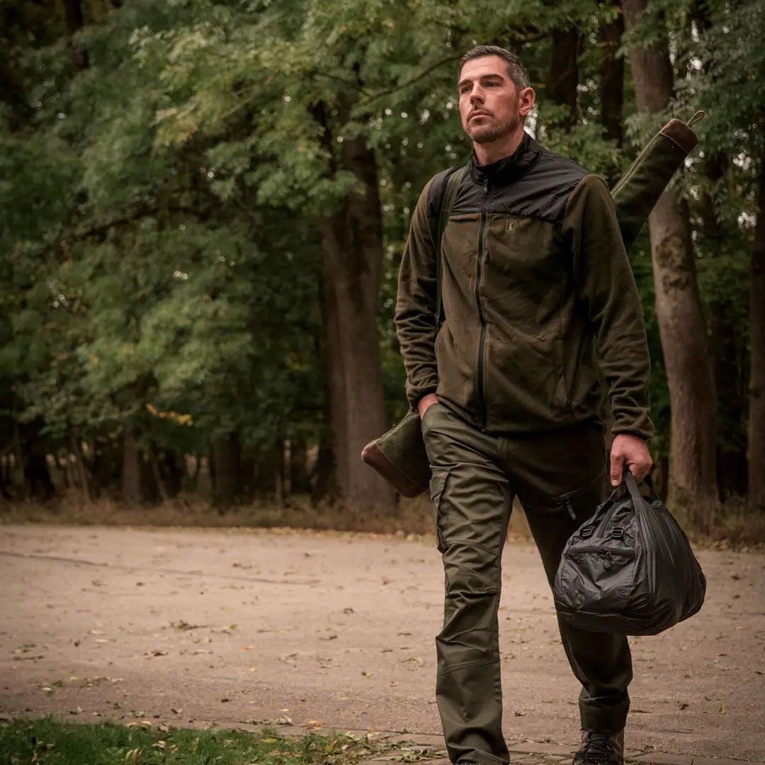 Man in Deerhunter Northward Fleece Jacket walking on a dirt path with a bag