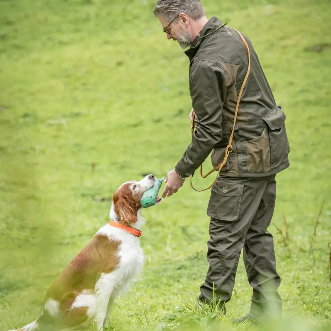 Man in Deerhunter Rogaland Trousers interacting with a spaniel in a grassy field