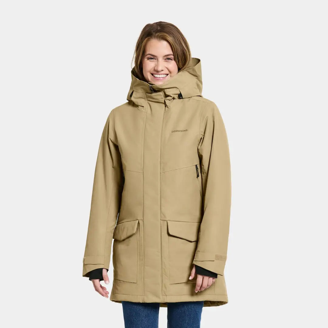 Smiling person in a beige Didriksons Frida Womens Parka with cozy front pockets