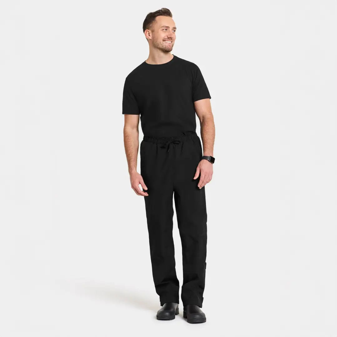 Man in a black jumpsuit showcasing stylish functional rain pants for outdoor adventures