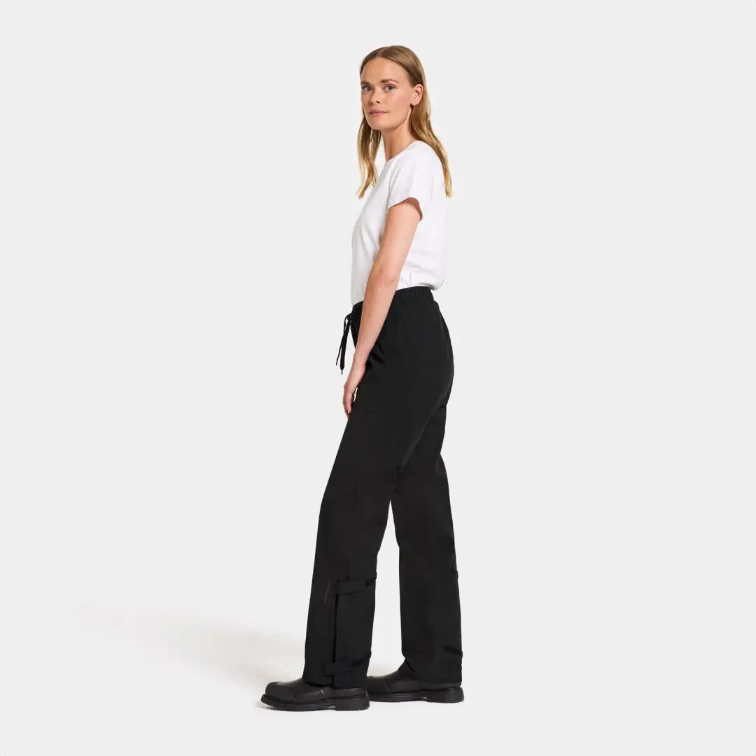 Woman in white tee and black wide-leg Didriksons Grit rain pants for functional style