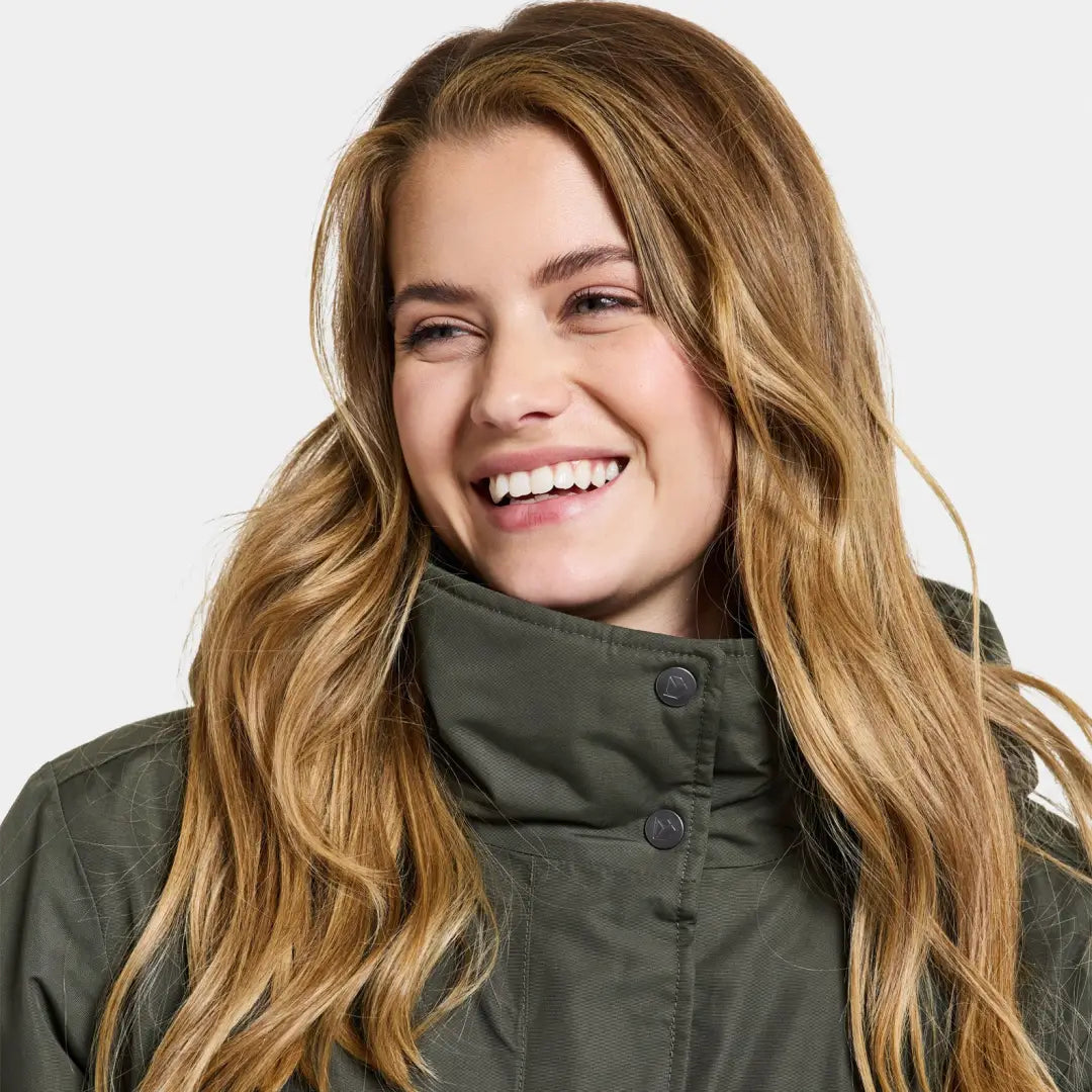 Smiling woman in a green Didriksons Josefine Womens Parka 2, showcasing classic parka style