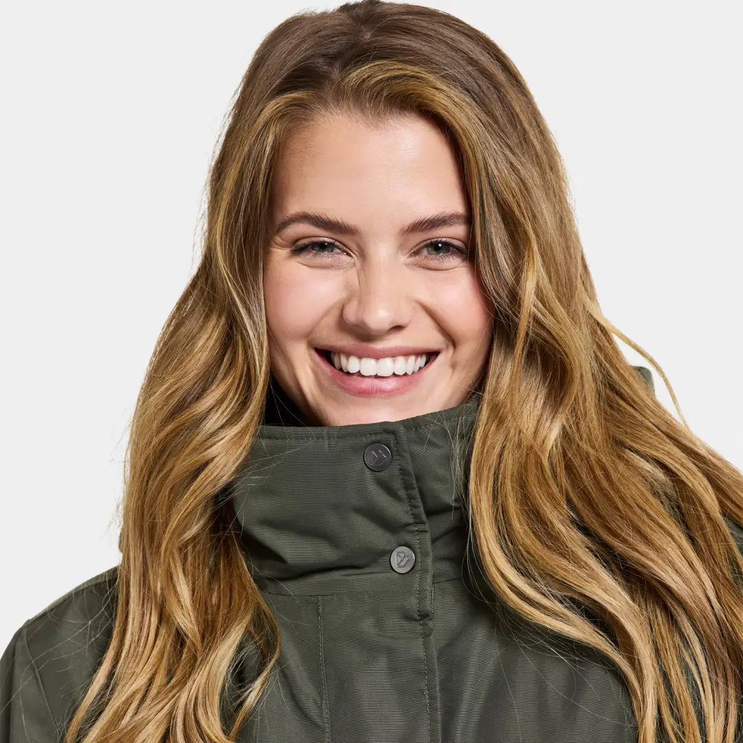 Smiling woman in a green Didriksons Josefine Womens Parka, rocking a classic parka style