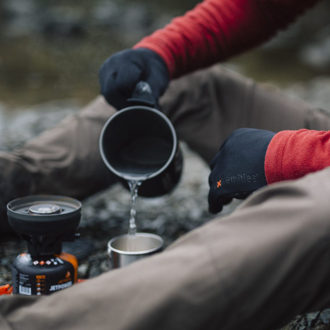 Person pouring water into a cup while wearing Extremities Waterproof Powerliner Gloves