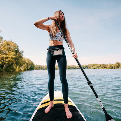 Woman paddleboarding with a stylish Fidlock Sling Bag Dry Bag for hassle-free adventures