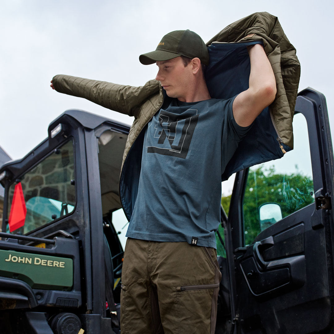 Man putting on a green jacket over a Harkila H-logo Short Sleeve T-Shirt for hunting