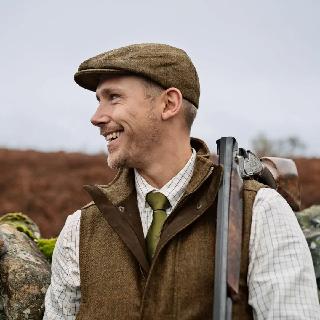 Smiling man in traditional hunting gear wearing a Härkila Kenmore Waistcoat with press button closure