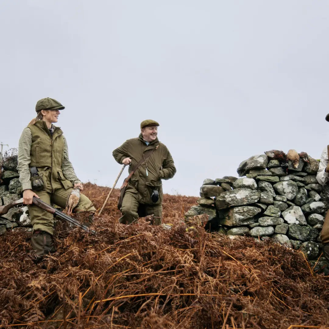 Two men in hunting gear by a stone wall, showcasing the Härkila Kenmore Waistcoat