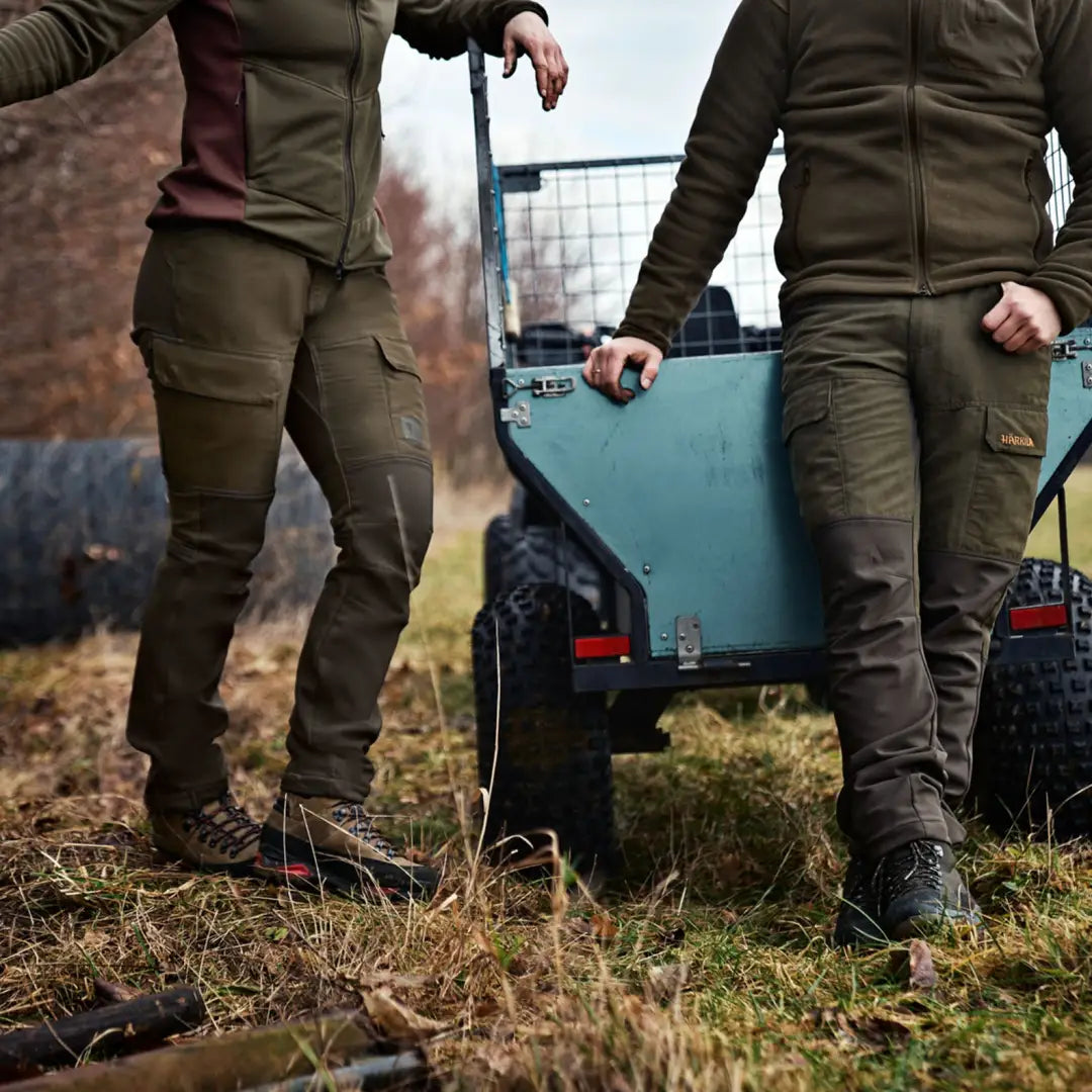 Blue utility cart between two people in olive outdoor gear and Harkila Scandinavian Trousers