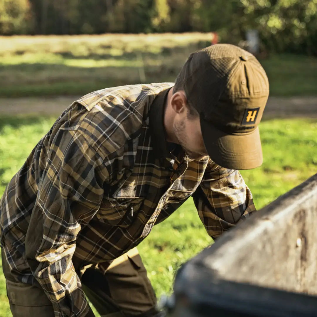 Person in a plaid Harkila Pajala Shirt with button closure examining something closely