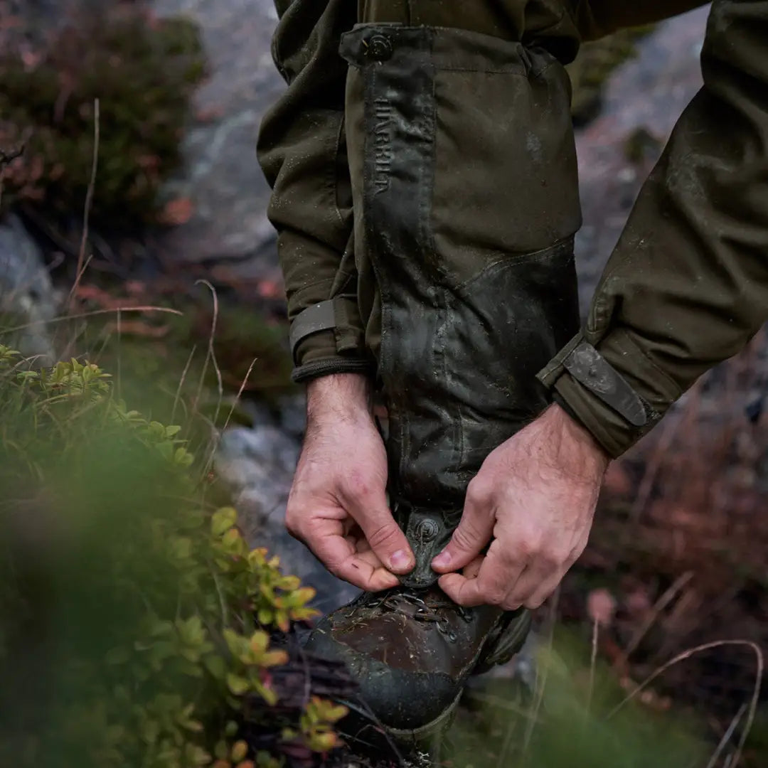 Hands tying laces of a rugged boot with Harkila Pro HWS Gaiters for outdoor adventures