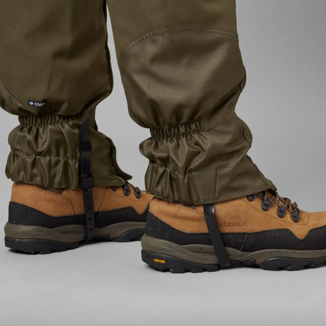 Brown hiking boots with olive-green Harkila Pro HWS gaiters for outdoor adventures